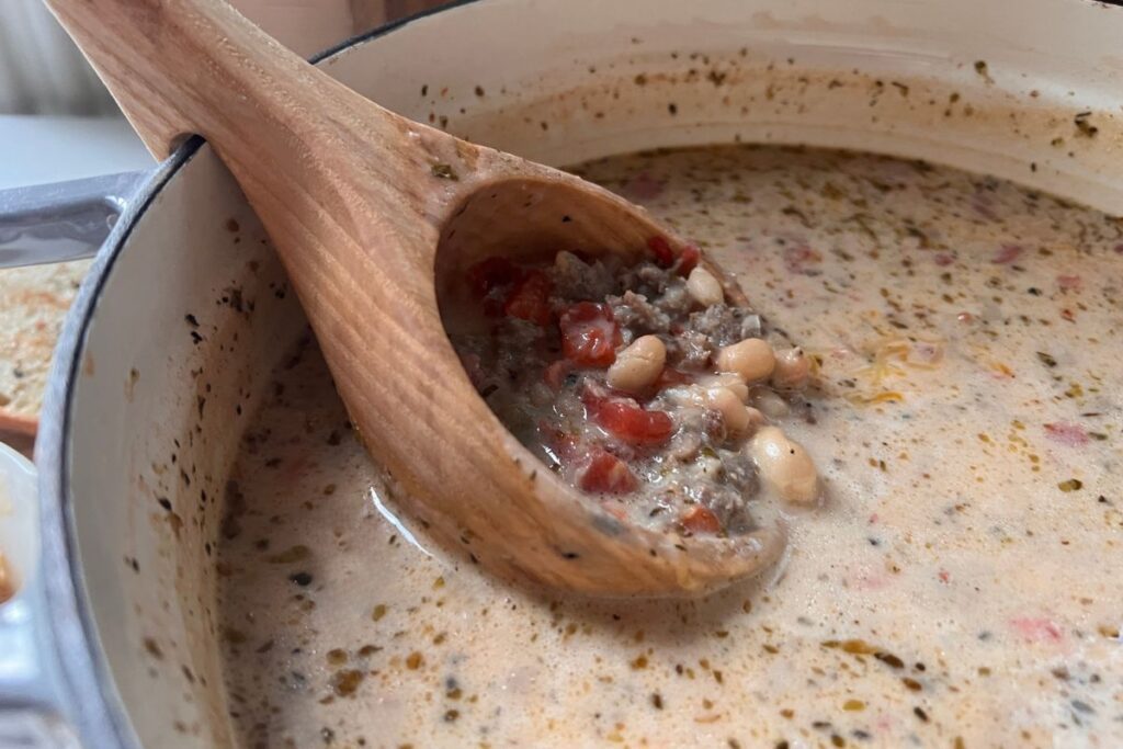 spoon full of creamy sausage and bean soup
