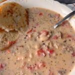 creamy bean and sausage soup in a bowl with bread