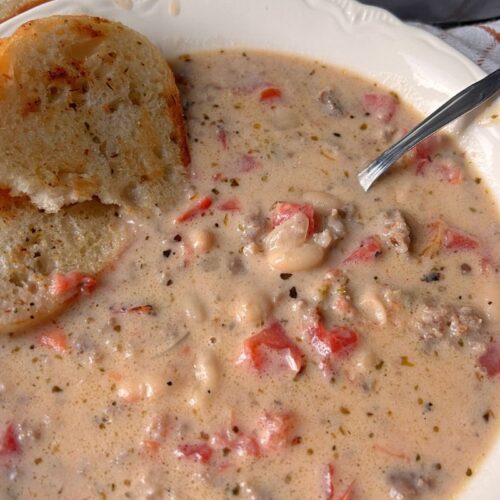 creamy bean and sausage soup in a bowl with bread
